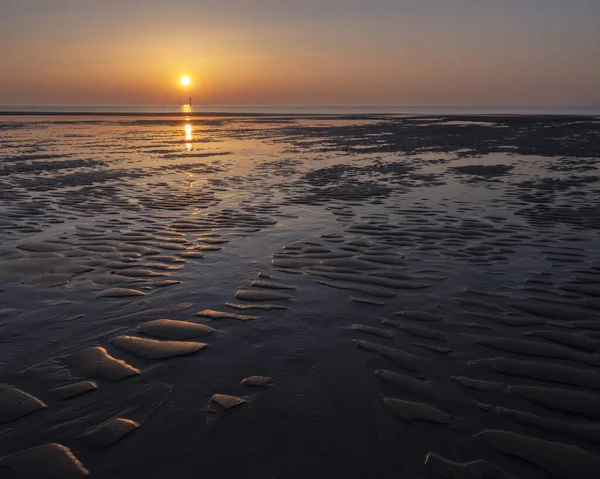 Padrão na areia e reflexão colorida de pôr do sol na água — Fotografia de Stock