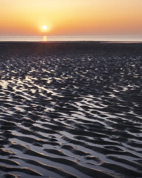 Padrão na areia e reflexão colorida de pôr do sol na água — Fotografia de Stock