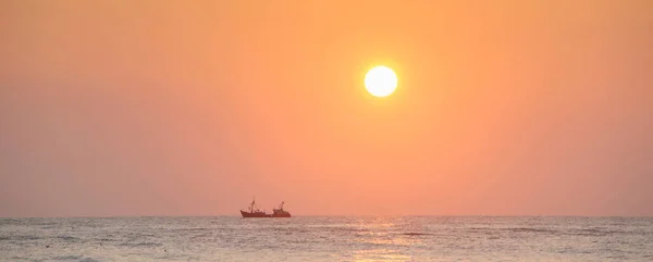 Σιλουέτα του αλιευτικού πλοίου κάτω από πορτοκαλί ουρανό κατά τη διάρκεια του ηλιοβασιλέματος στη θάλασσα — Φωτογραφία Αρχείου