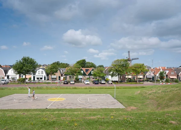 Ludzie grają w koszykówkę w holenderskiej wiosce z wiatrakiem oudeschild na holenderskiej wyspie Texel w Holandii — Zdjęcie stockowe