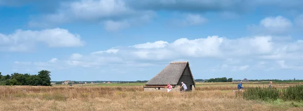 People on bicycle near typical barn on the island of texel in the netherlands — Stock Photo, Image