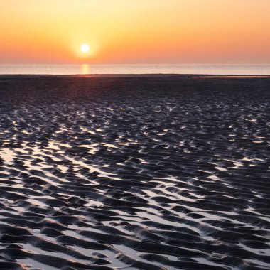 Kumda desen ve suda güneşin batışının renkli yansıması