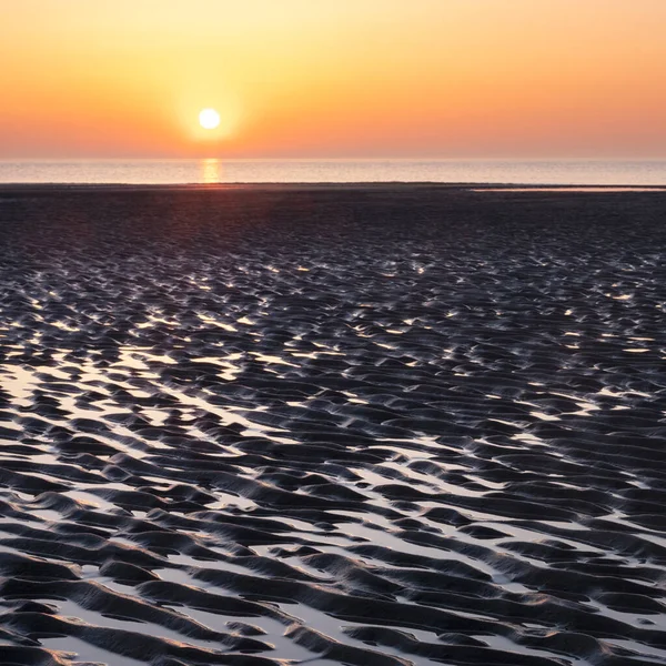 Padrão na areia e reflexão colorida de pôr do sol na água — Fotografia de Stock