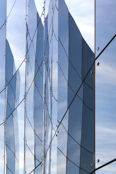 Lot of reflections in glass facade of building — Stock Photo, Image