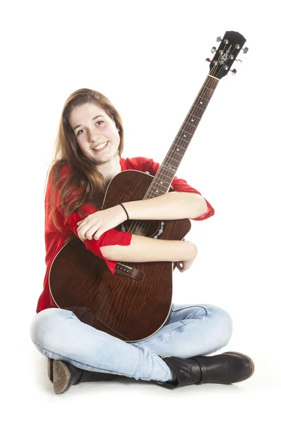 Teenage holds arms around guitar in studio — Stock Photo, Image