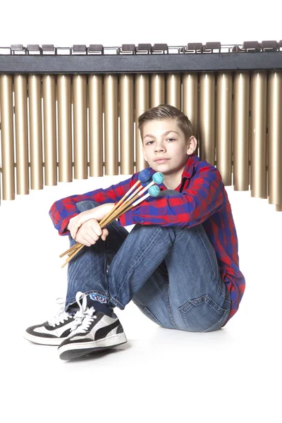 Teenage boy sits under marimba in studio — Stock Photo, Image