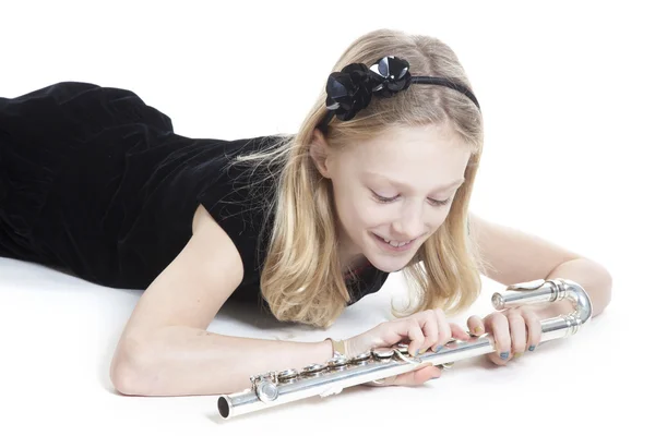 Young blond girl holds flute lying down in studio — Stock Photo, Image