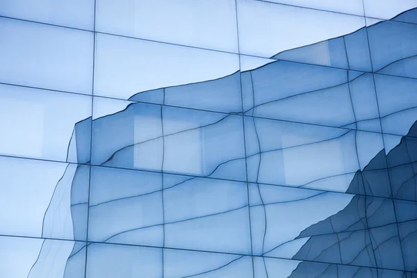 Façade du bâtiment moderne en verre avec des reflets du ciel bleu et — Photo