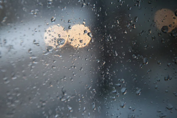 Фары автомобиля и отражения, видимые через стекло с дождём — стоковое фото