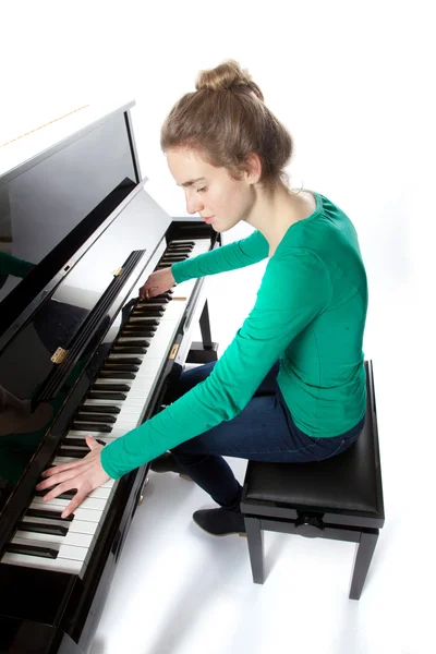 Teenage girl plays piano in green shirt — Stock Photo, Image