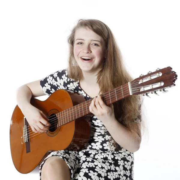 Smiling teenage girl in dress plays the guitar in studio — Stock Photo, Image