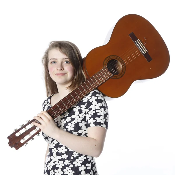 Teenage girl in dress holds guitar on shoulder in studio — Stock Photo, Image