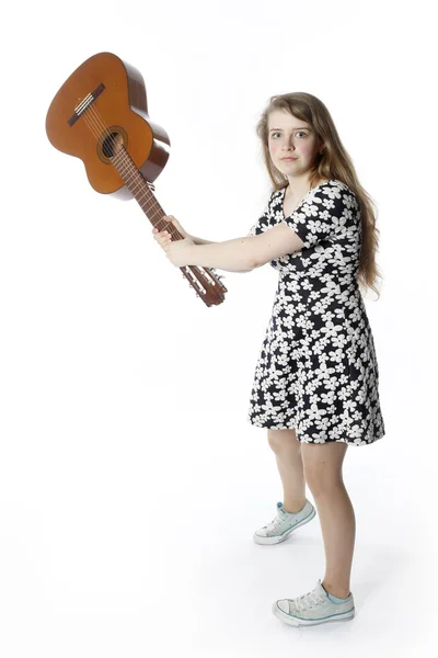 Teenage girl in dress swings guitar in studio — Stock Photo, Image