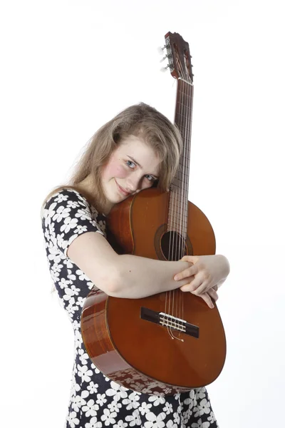 Smiling teenage girl in dress holds guitar in studio — Stock Photo, Image