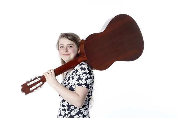 Teenage girl in dress holds guitar on shoulder in studio — Stock Photo, Image