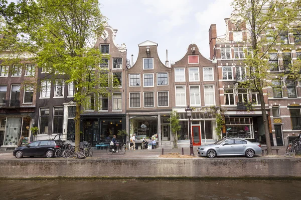 People enjoy spring sunshine in front of canal houses in amsterd — Stock Photo, Image