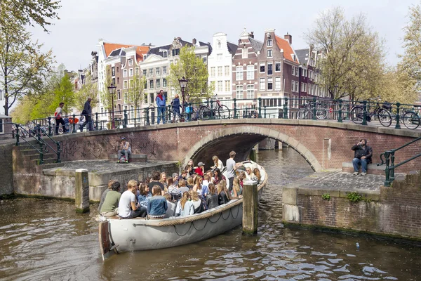 Tekne köprü altında genç insanlarla dolu amsterdam kanal o açık — Stok fotoğraf