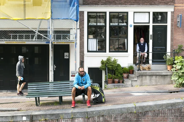 Anciano se sienta con dos perros en la puerta de la casa del canal en medio — Foto de Stock