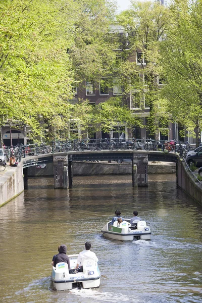 Tourists paddle in water bikes in Amsterdam canal in spring — Stock Photo, Image