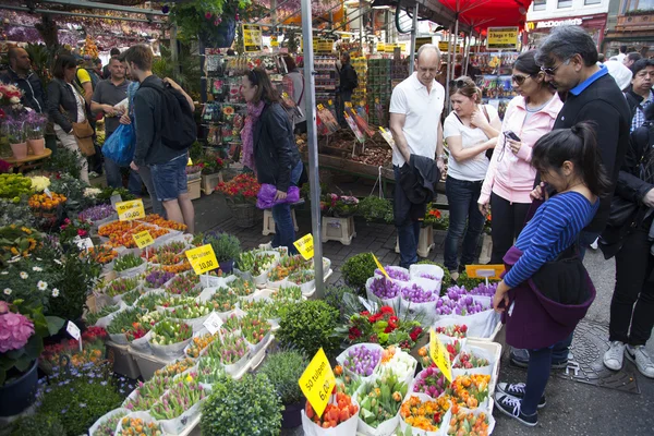 Toeristen kijken koopwaar op amsterdam bloemenmarkt — Stockfoto