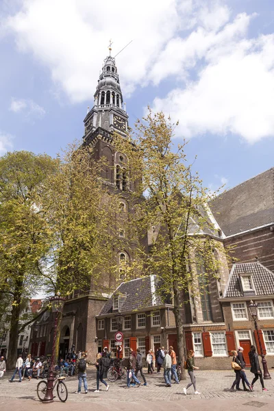 Πολλοί άνθρωποι στην πλατεία δίπλα στην παλαιά εκκλησία στο Αμστερνταμ κόκκινο φως — Φωτογραφία Αρχείου