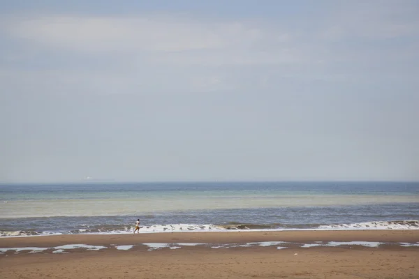 Uomo corre sulla spiaggia del mare del nord in Olanda — Foto Stock