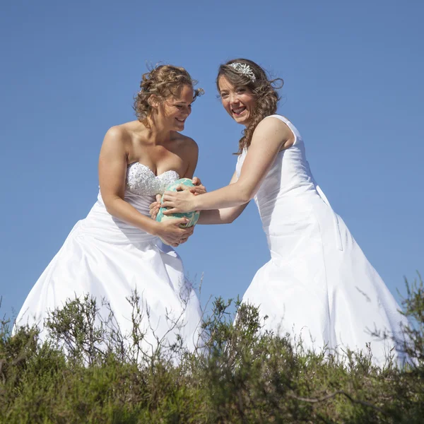 Дві наречені з м'ячем регбі на фоні блакитного неба — стокове фото