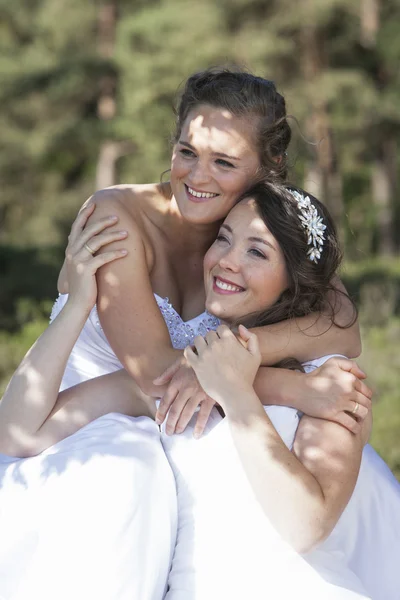 Dos novias sonríen y se abrazan en la naturaleza — Foto de Stock
