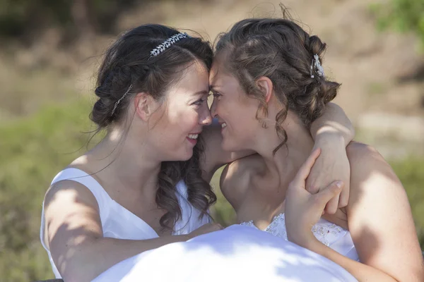 Two brides smile and embrace in nature surroundings — Stock Photo, Image