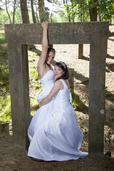 Picture of two brides under concrete object in nature surroundin — Stock Photo, Image