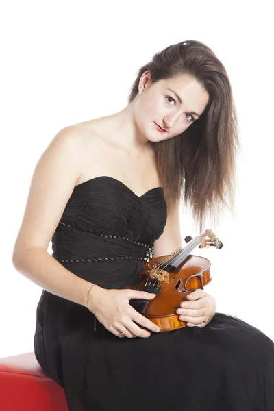 Brunette sits and holds violin in studio against white backgroun — 스톡 사진