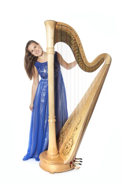 Young caucasian woman stands with concert harp in studio against — Stok fotoğraf