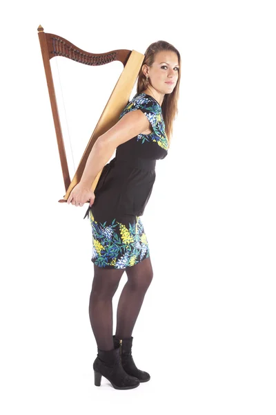 Young caucasian woman stands and holds small harp in studio agai — Stock Photo, Image