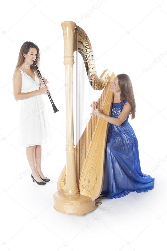 two young women in studio with harp and clarinet against white b