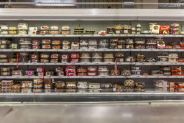 Süpermarkette çeşit çeşit kekleri olan bir vitrin. Bulanık. Ön görünüm.