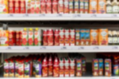 Süpermarketteki raflarda çeşitli meyve suları var. Bulanık. Ön görünüm.