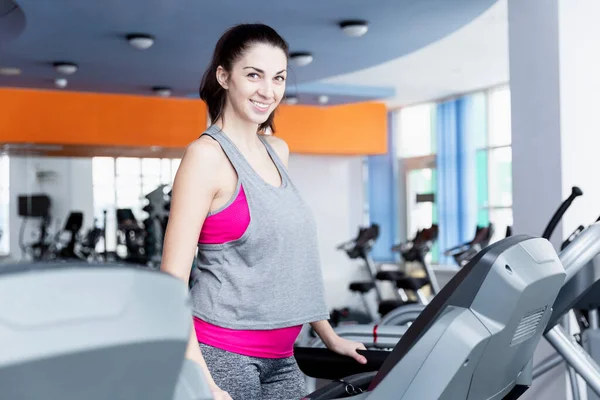 stock image Smiling young woman on a treadmill in the gym. Active lifestyle and health.