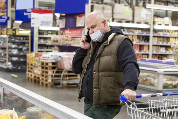 Мужчина Медицинской Маске Большом Супермаркете Разговаривает Телефону Трудность Выбора Пандемия — стоковое фото