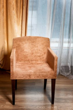 Pencerenin arka planında kahverengi koltuk. Dikey.