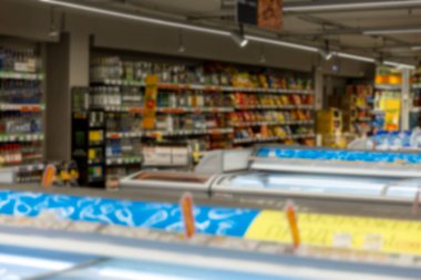 Süpermarketin içi. İçkili raflar, dondurulmuş yiyeceklerle dolu konteynırlar. Bulanık.