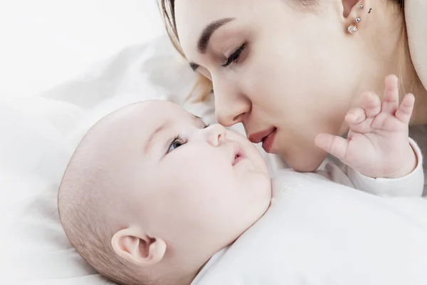 A young mom kisses a newborn baby. Love and tenderness. Close-up.