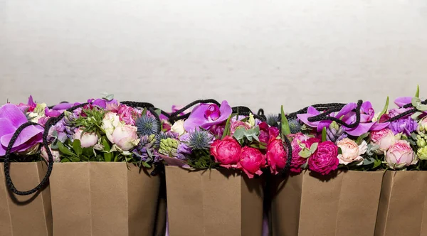 A row of paper bags with flower arrangements. Gifts for the women\'s spring holiday. Space for text.