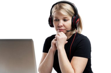 Kulaklık ve mikrofonlu sarışın bir kadın elinde dizüstü bilgisayarla masada oturuyor. Uzaktan çalışma, uzaktan öğrenme ve destek hizmeti. Beyaz arkaplanda izole.