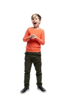 9 yaşında kot giyen ve turuncu kazak giyen bir çocuk bağırıyor. Tam yükseklik. Beyaz arka planda izole edilmiş. Dikey.