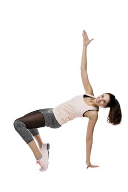 Spor giyim bölümünde gülümseyen genç bir kadın egzersiz yapıyor. Spor, aktivite ve hareket. Beyaz arkaplanda izole.