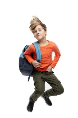 9 yaşında, turuncu süveter ve sırt çantasıyla şık bir saç stili olan bir çocuk atlıyor. Okula dönelim. Beyaz arka planda izole edilmiş. Dikey.