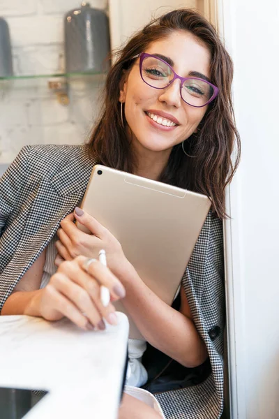 Beautiful smiling young woman with laptop in a cafe. Online business, training and social networks. Vertical.