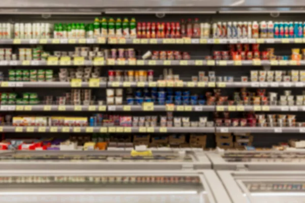 Shelves with a variety of dairy products in the supermarket. Blurred.