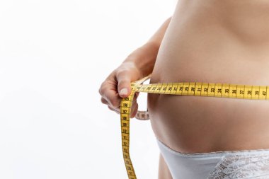 Young woman measures the volume of the abdomen with a tape. Health and proper nutrition. White background. Space for text.