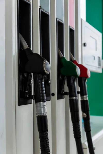 A row of pistols with gasoline at the gas station. Close-up. Vertical.